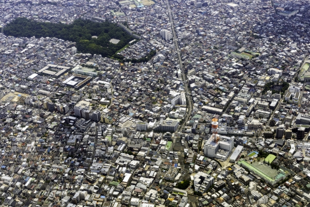 Aerial view of a densely packed city with grid-like blocks and a long road slicing through the center.